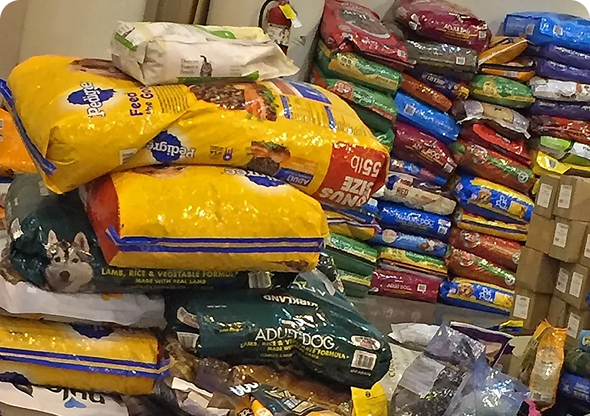 Stacks of various large bags of dog food piled and organized in a store. Stacks of various large bags of dog food piled and organized in a store.