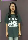 A woman standing in front of a wall wearing a t-shirt.