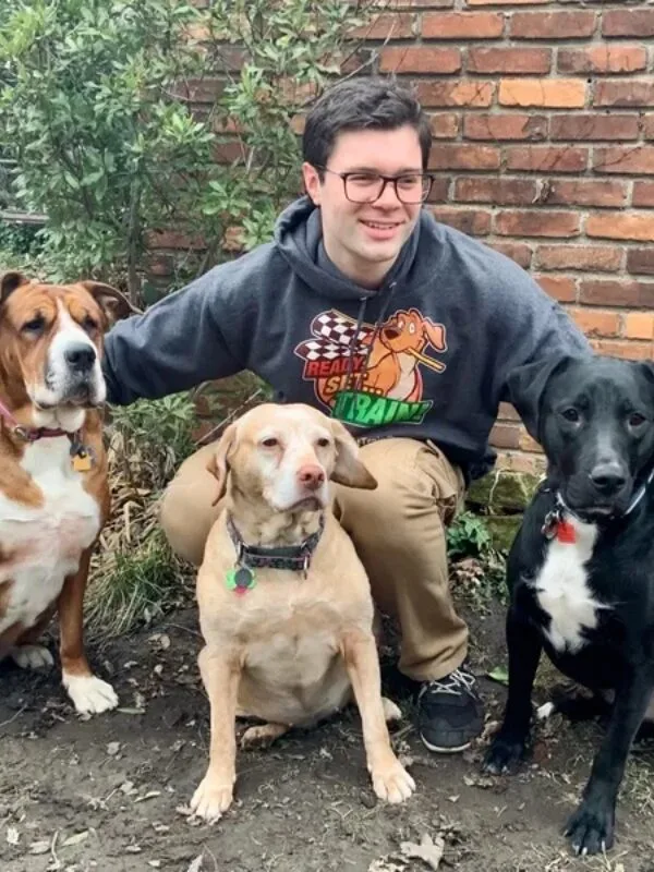 max A man kneeling down next to four dogs.