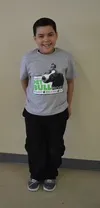 A man standing in front of a wall wearing a t-shirt.